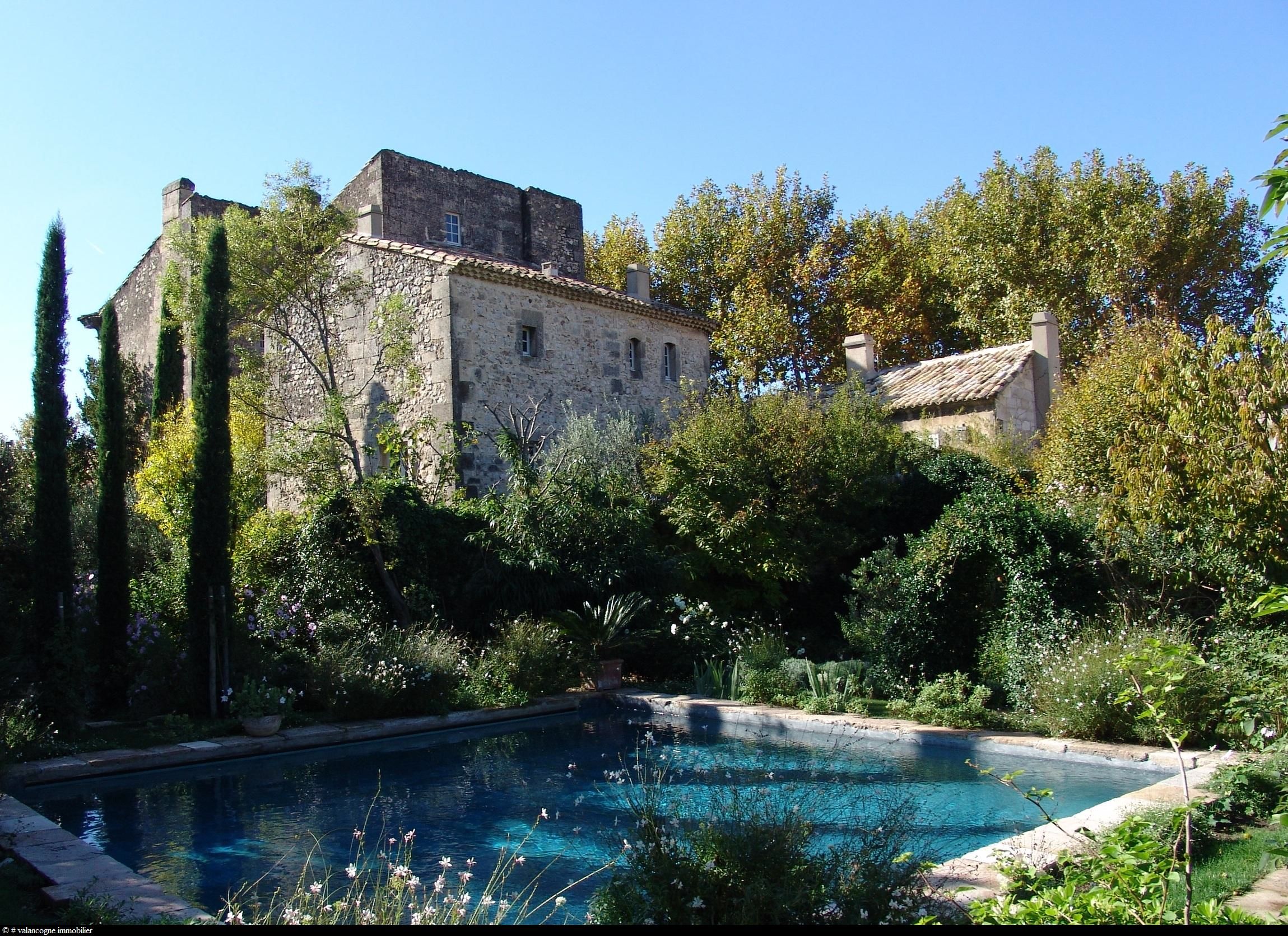 Provençal garden with sun loungers, lush greenery and a stone pathway leading to a pool